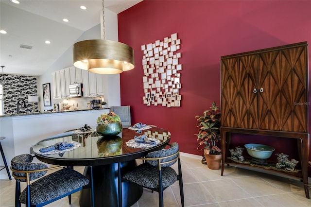 dining area with light tile patterned flooring, sink, and high vaulted ceiling