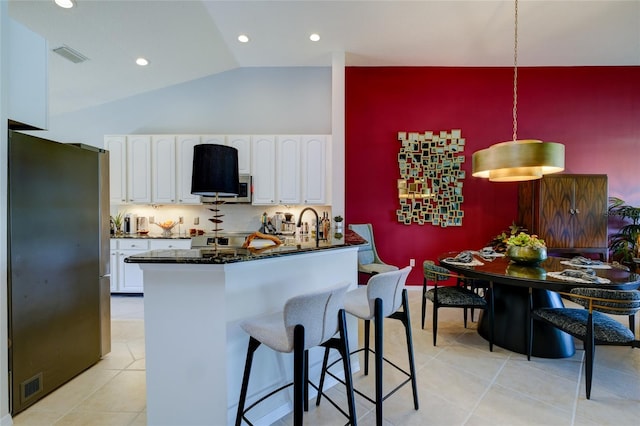 kitchen featuring pendant lighting, lofted ceiling, kitchen peninsula, white cabinetry, and appliances with stainless steel finishes