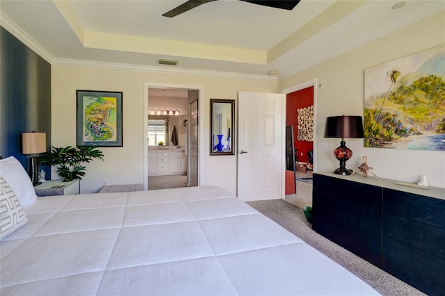 bedroom with a raised ceiling, ceiling fan, ornamental molding, ensuite bath, and light colored carpet