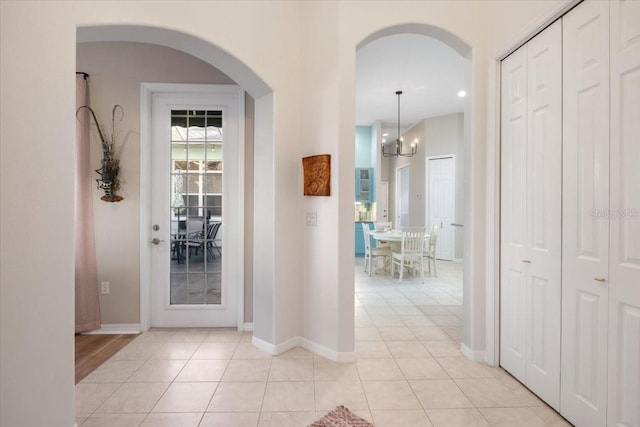 entryway with light tile patterned floors and a notable chandelier