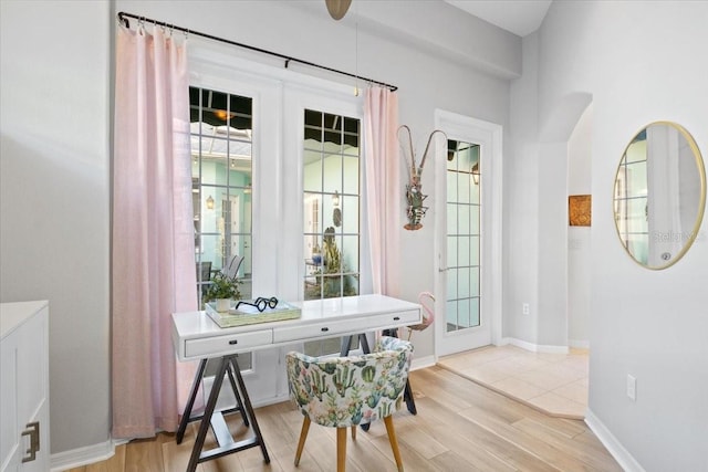 home office with light wood-type flooring, a wealth of natural light, and french doors