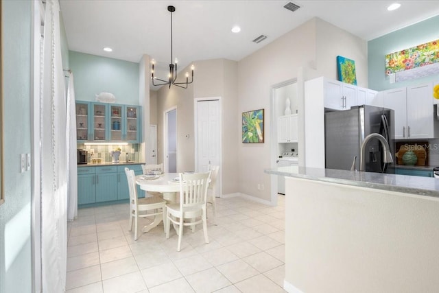 kitchen with stainless steel fridge, blue cabinets, white cabinetry, light tile patterned floors, and washer / dryer