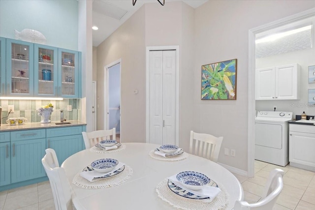 tiled dining area with a high ceiling and washer / clothes dryer