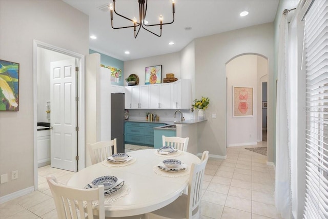 dining space featuring a notable chandelier, sink, light tile patterned floors, and a healthy amount of sunlight