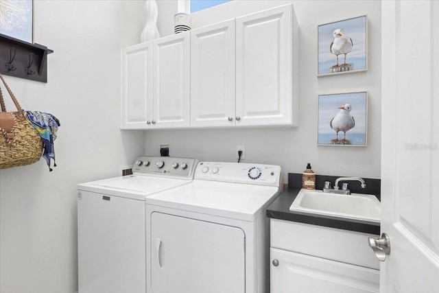 laundry area featuring sink, washing machine and clothes dryer, and cabinets