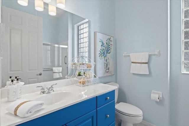 bathroom with an enclosed shower, vanity, and toilet