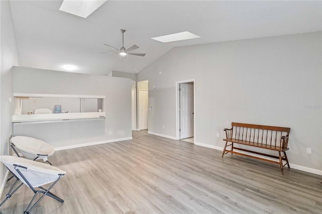 sitting room featuring lofted ceiling with skylight, light wood-type flooring, and ceiling fan