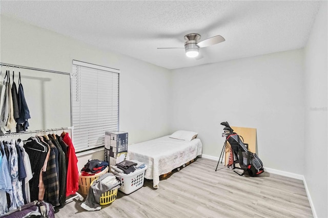 bedroom featuring light hardwood / wood-style floors, a textured ceiling, and ceiling fan