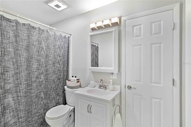 bathroom with vanity, toilet, a textured ceiling, and walk in shower