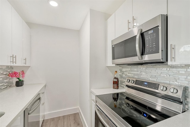 kitchen with stainless steel appliances, light wood-type flooring, tasteful backsplash, and white cabinetry