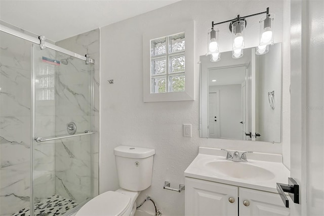 bathroom featuring vanity, a shower with shower door, and toilet