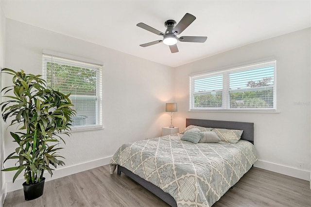 bedroom featuring ceiling fan, multiple windows, and hardwood / wood-style floors