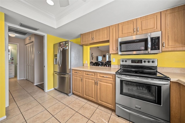 kitchen with ornamental molding, light tile patterned floors, and stainless steel appliances