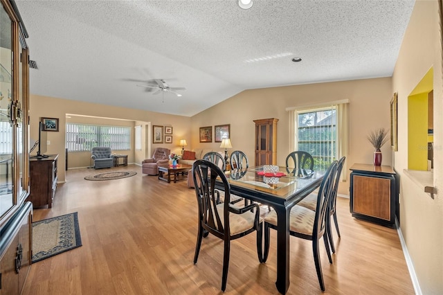 dining room with ceiling fan, a textured ceiling, light wood-type flooring, and lofted ceiling