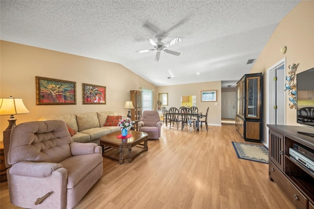 living room with a textured ceiling, light wood-type flooring, and ceiling fan