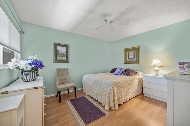 bedroom featuring a textured ceiling, light wood-type flooring, and ceiling fan