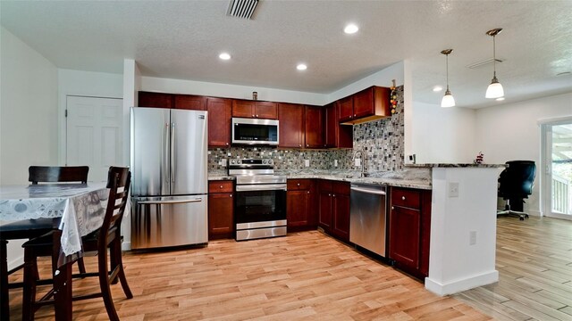 823 32nd Ave E, Bradenton, FL 34208 - kitchen with stainless steel appliances, light wood-style flooring, decorative backsplash, light stone countertops, and a textured ceiling
