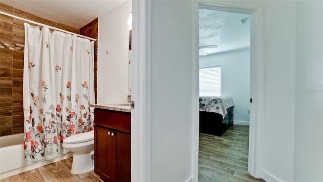 full bathroom with wood-type flooring, a textured ceiling, shower / tub combo, vanity, and toilet