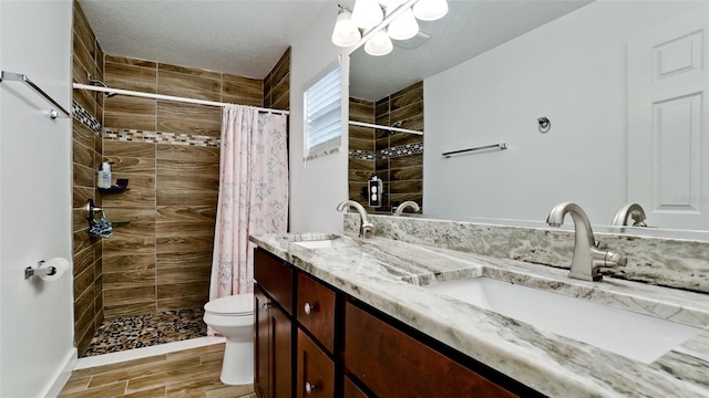 bathroom with a textured ceiling, curtained shower, vanity, and toilet