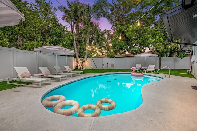 pool at dusk featuring a lawn and a patio area