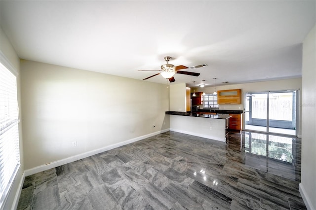 unfurnished living room featuring ceiling fan and sink