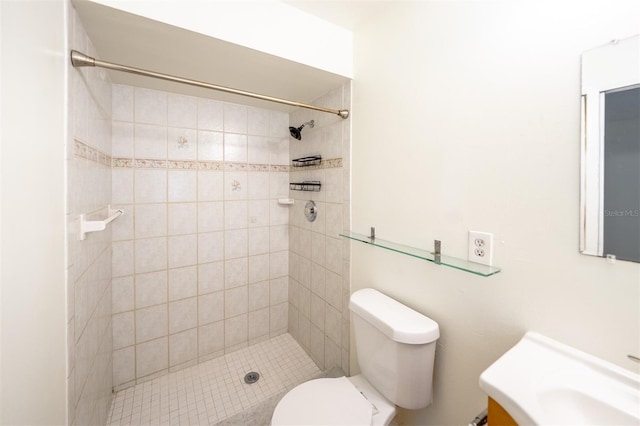 bathroom featuring a tile shower, vanity, and toilet