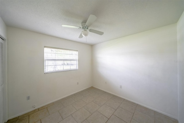 unfurnished room with ceiling fan, light tile patterned floors, and a textured ceiling