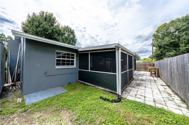 back of house featuring a sunroom and a lawn