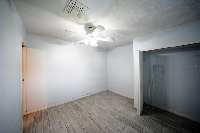 empty room featuring ceiling fan, a textured ceiling, and light hardwood / wood-style floors