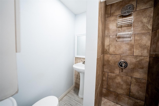 bathroom with hardwood / wood-style floors, tiled shower, and toilet