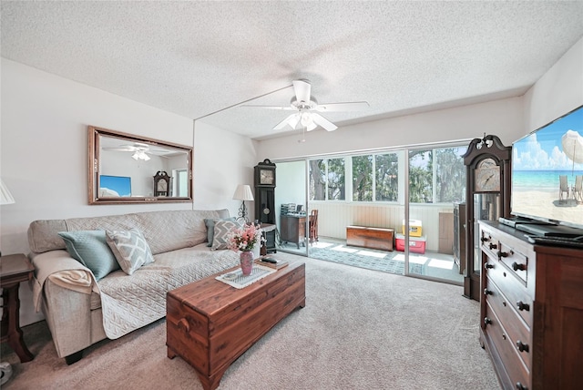 living room featuring ceiling fan, light colored carpet, and a textured ceiling