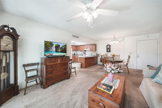 carpeted living room with a textured ceiling and ceiling fan with notable chandelier