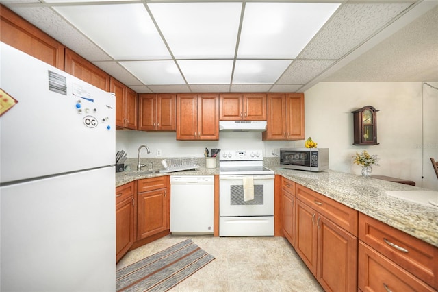 kitchen featuring a paneled ceiling, white appliances, light stone countertops, and sink