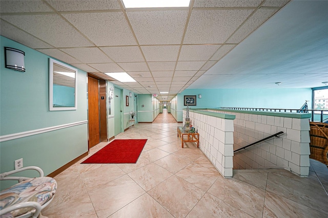 interior space with a paneled ceiling and tile patterned flooring