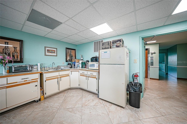 kitchen featuring a paneled ceiling, sink, white appliances, and white cabinetry