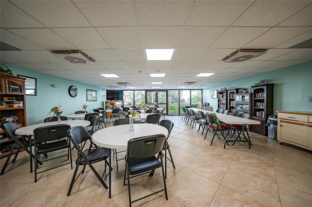 dining area with a drop ceiling and light tile patterned floors