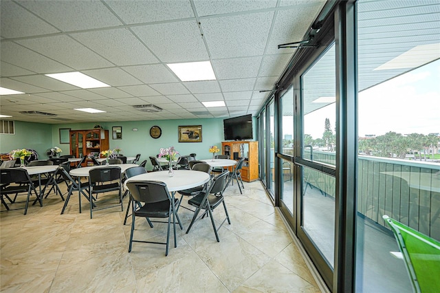 dining space featuring a drop ceiling and expansive windows