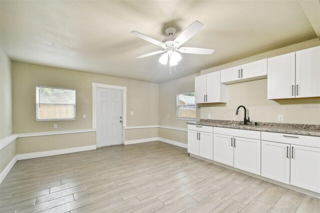 3419 19th St E, Bradenton, FL 34208 - kitchen featuring white cabinets, light wood-style flooring, a sink, baseboards, and ceiling fan