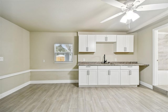 kitchen featuring ceiling fan, light stone countertops, light wood-type flooring, and white cabinetry