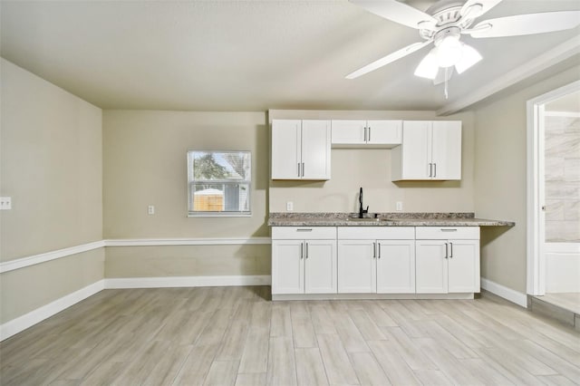 3419 19th St E, Bradenton, FL 34208 - kitchen with a sink, ceiling fan, light wood-style flooring, white cabinets, and baseboards