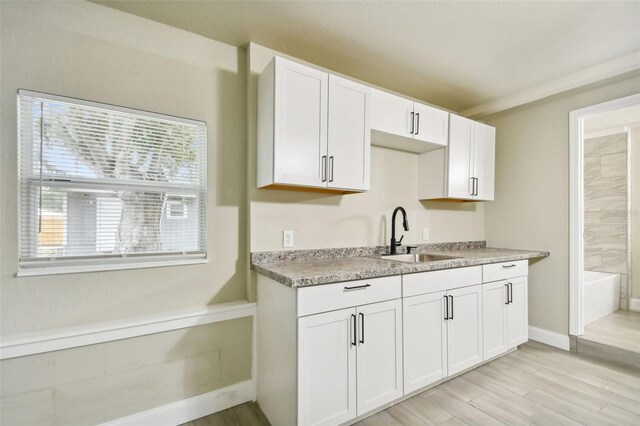 3419 19th St E, Bradenton, FL 34208 - kitchen with white cabinets, baseboards, a sink, and light wood-style floors