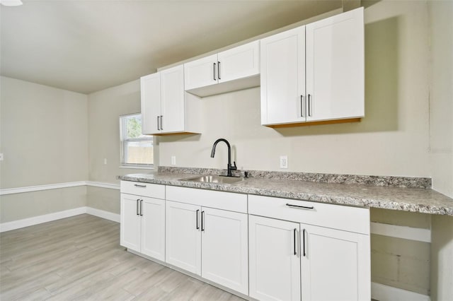 3419 19th St E, Bradenton, FL 34208 - kitchen with a sink, light wood-type flooring, baseboards, white cabinetry, and light countertops