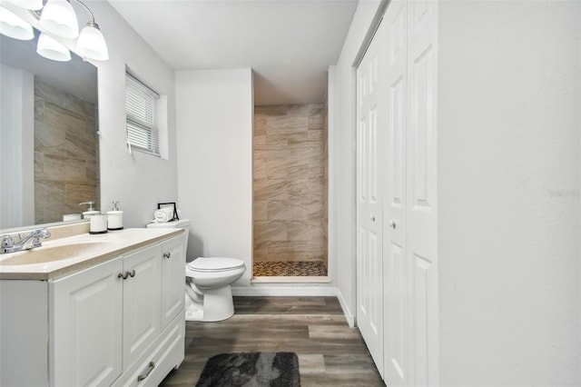 bathroom featuring a tile shower, vanity, toilet, and hardwood / wood-style flooring