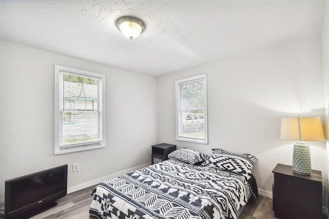 bedroom with wood-type flooring and multiple windows