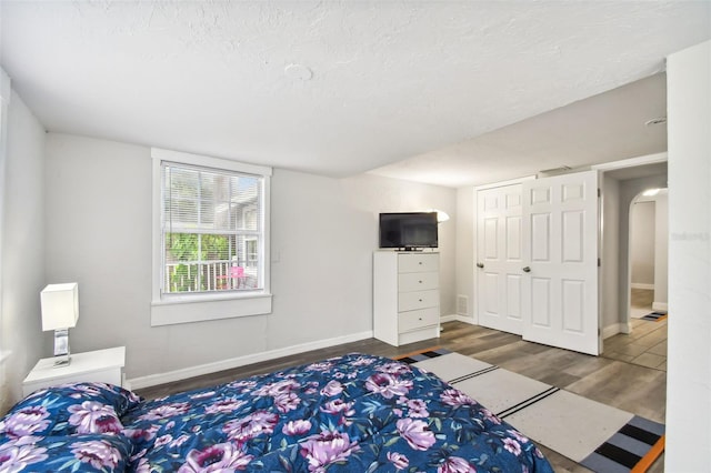 bedroom with a closet, dark hardwood / wood-style floors, and a textured ceiling