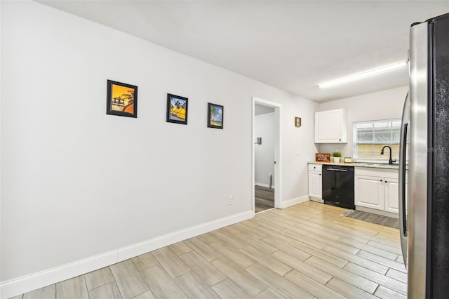 3419 19th St E, Bradenton, FL 34208 - kitchen featuring light countertops, white cabinets, wood finish floors, black dishwasher, and freestanding refrigerator
