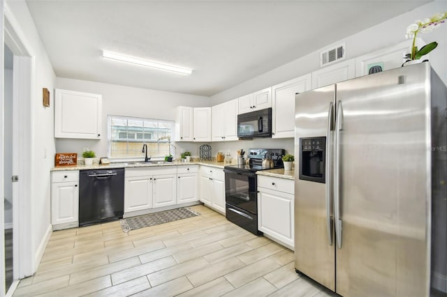 kitchen featuring black appliances, white cabinetry, sink, and light stone counters