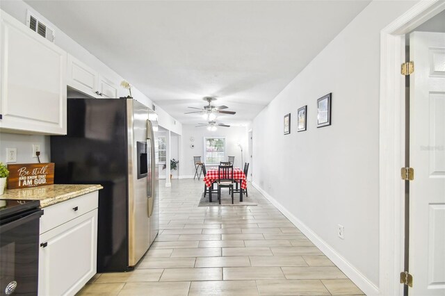 kitchen with black electric range, white cabinetry, light stone countertops, ceiling fan, and stainless steel fridge