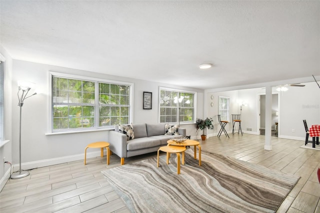 living room with a textured ceiling, ceiling fan, and light hardwood / wood-style flooring