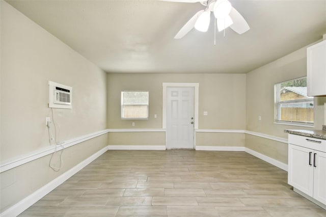 spare room featuring light hardwood / wood-style flooring, a wall unit AC, and ceiling fan